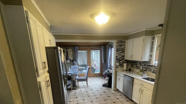 kitchen featuring tasteful backsplash, stainless steel appliances, light countertops, white cabinetry, and a sink