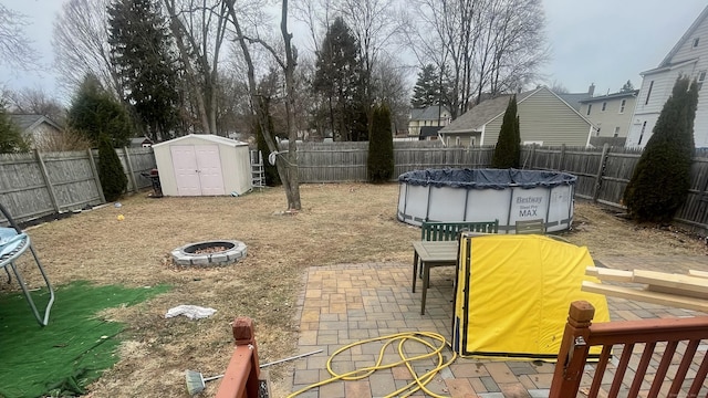 view of yard with an outbuilding, an outdoor fire pit, a fenced backyard, a storage shed, and a fenced in pool