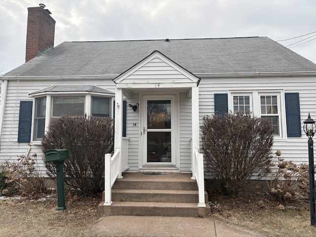 view of front of house with a shingled roof and a chimney