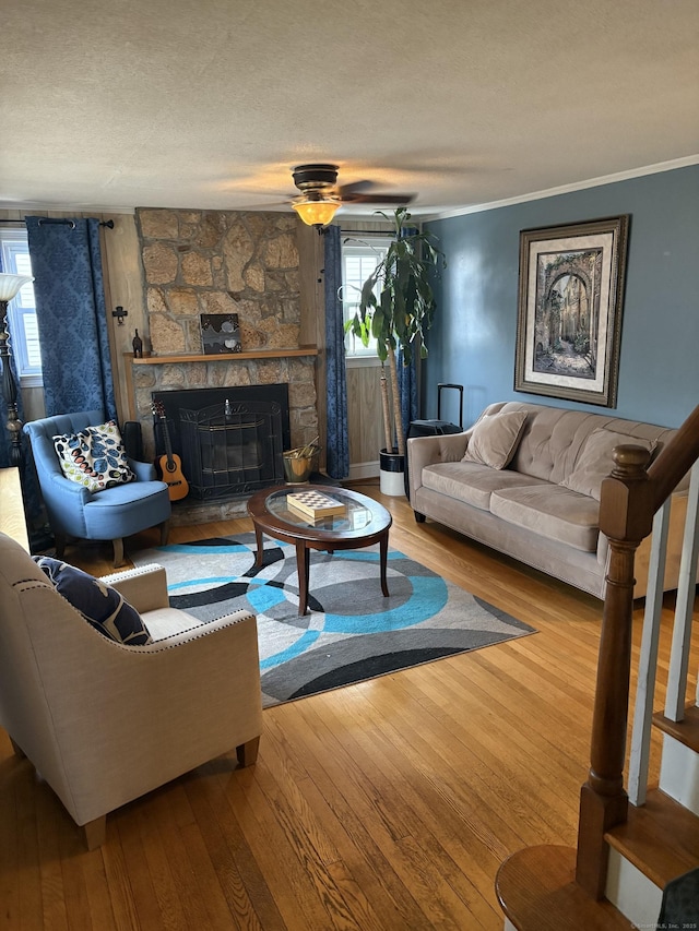 living room with plenty of natural light, wood-type flooring, a fireplace, and crown molding