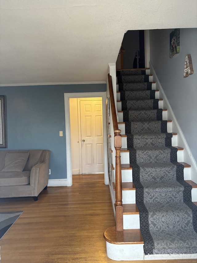 staircase featuring ornamental molding, baseboards, and wood finished floors