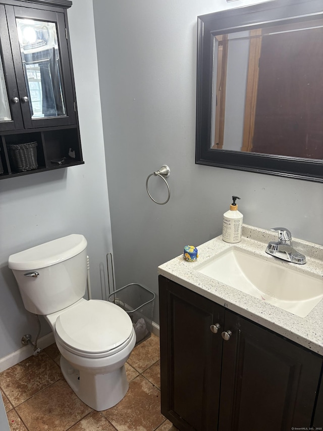 half bathroom featuring baseboards, vanity, toilet, and tile patterned floors