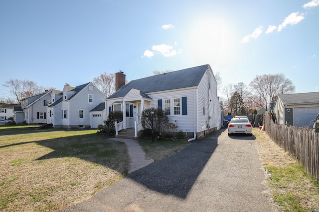 view of front of property featuring a residential view, a chimney, driveway, a front yard, and fence