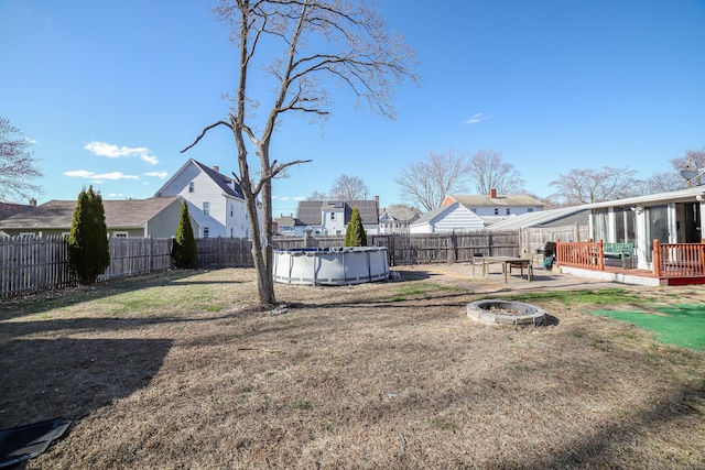 view of yard with an outdoor fire pit, a fenced backyard, a fenced in pool, and a wooden deck