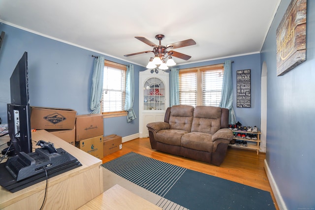 living room featuring wood finished floors, baseboards, ornamental molding, and ceiling fan