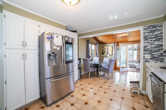 kitchen featuring ornamental molding, light countertops, white cabinets, decorative backsplash, and appliances with stainless steel finishes
