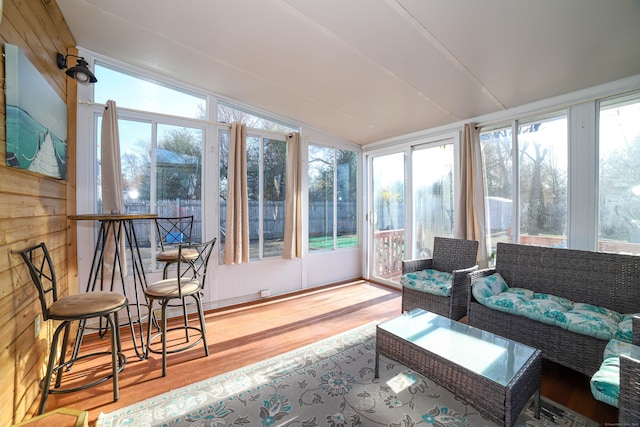 sunroom / solarium with wood finished floors, lofted ceiling, and a healthy amount of sunlight