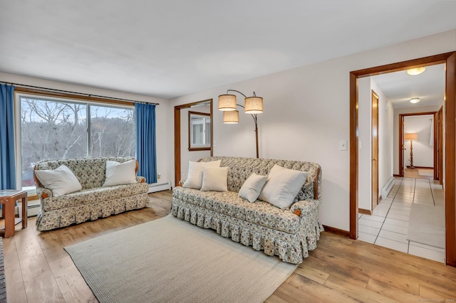 living room with a baseboard radiator, light wood-style flooring, and baseboards