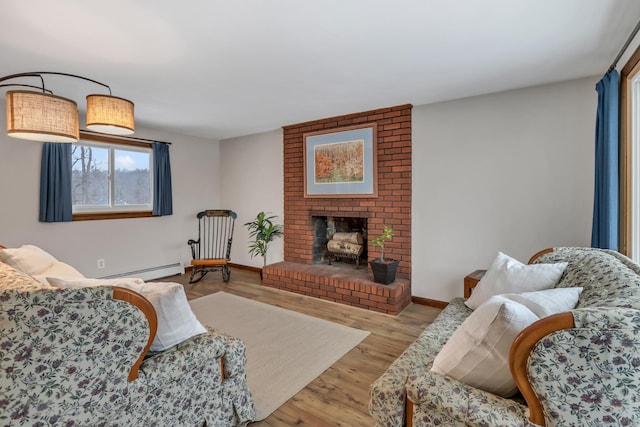 living room featuring a baseboard radiator, a brick fireplace, light wood-style flooring, and baseboards