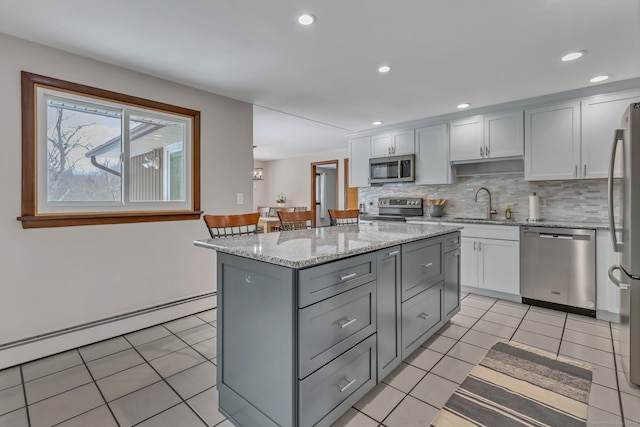 kitchen featuring a baseboard radiator, a sink, a kitchen island, appliances with stainless steel finishes, and backsplash