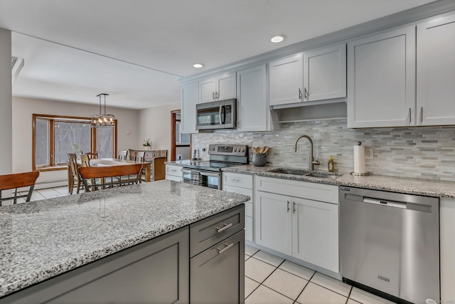 kitchen featuring light tile patterned floors, stainless steel appliances, decorative backsplash, a sink, and light stone countertops