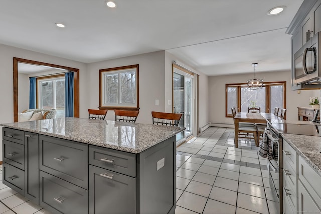 kitchen featuring light tile patterned flooring, gray cabinetry, stainless steel appliances, light stone countertops, and pendant lighting