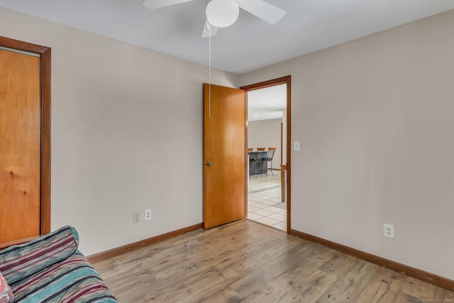 interior space featuring baseboards, a ceiling fan, and light wood-style floors