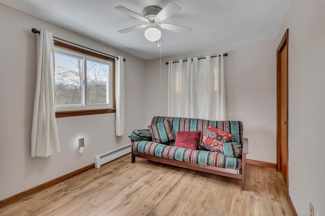 sitting room featuring a baseboard radiator, ceiling fan, light wood-style flooring, and baseboards