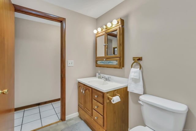 half bathroom featuring baseboards, vanity, toilet, and tile patterned floors