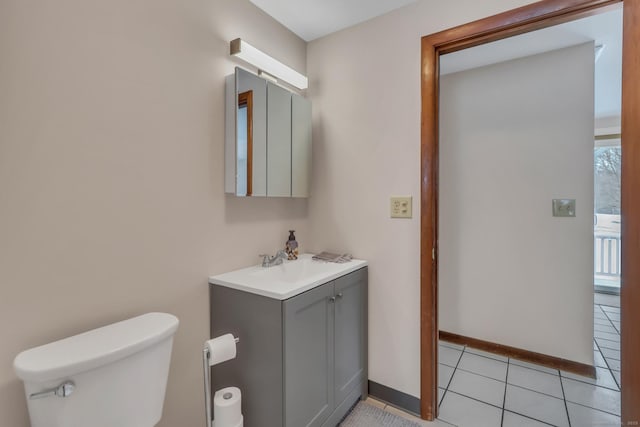 half bathroom featuring tile patterned flooring, vanity, toilet, and baseboards