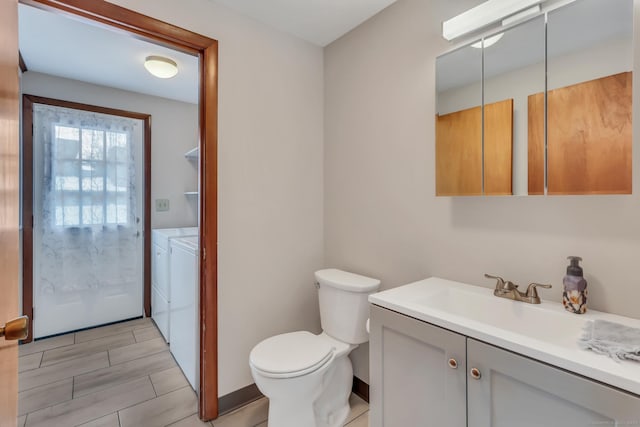 half bath with toilet, washing machine and dryer, and vanity