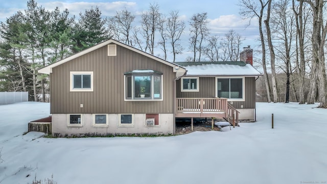 snow covered property featuring a deck and a chimney