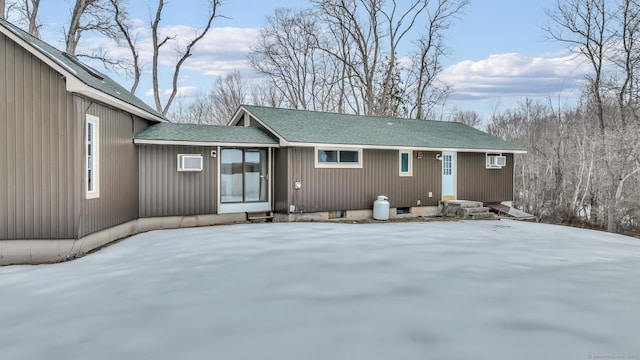 snow covered rear of property featuring roof with shingles