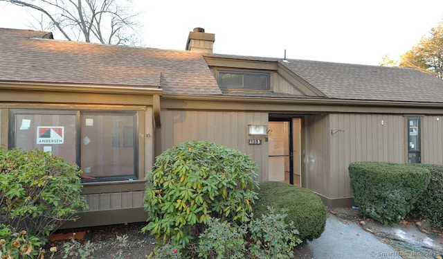 property entrance featuring roof with shingles and a chimney