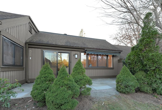 back of property featuring a patio and roof with shingles