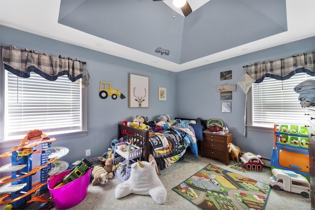 bedroom featuring carpet floors, a tray ceiling, a baseboard heating unit, and a ceiling fan