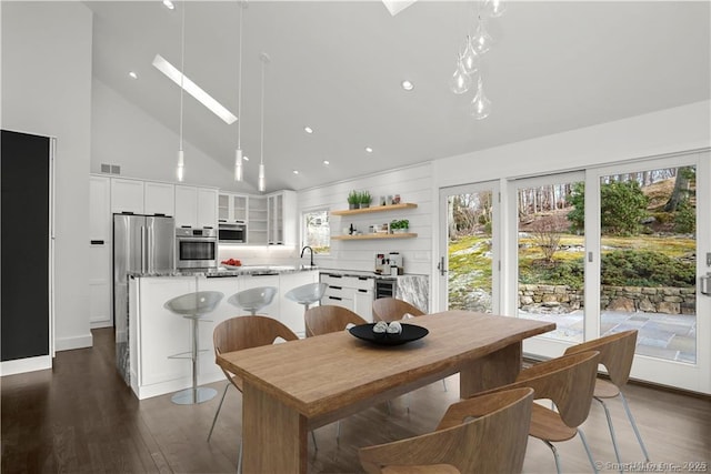 dining room with a skylight, visible vents, dark wood-style flooring, high vaulted ceiling, and recessed lighting