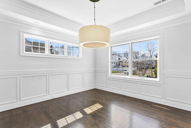 unfurnished dining area with plenty of natural light, ornamental molding, a decorative wall, wainscoting, and dark wood-type flooring