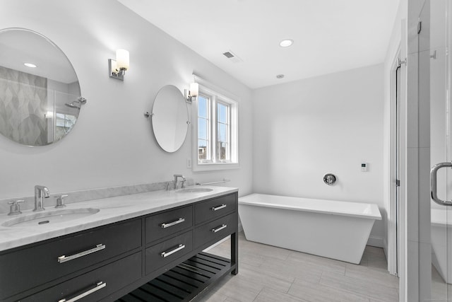 bathroom with double vanity, a shower stall, a soaking tub, and recessed lighting