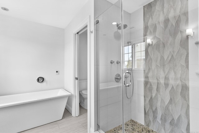 bathroom with a shower stall, toilet, and a freestanding tub