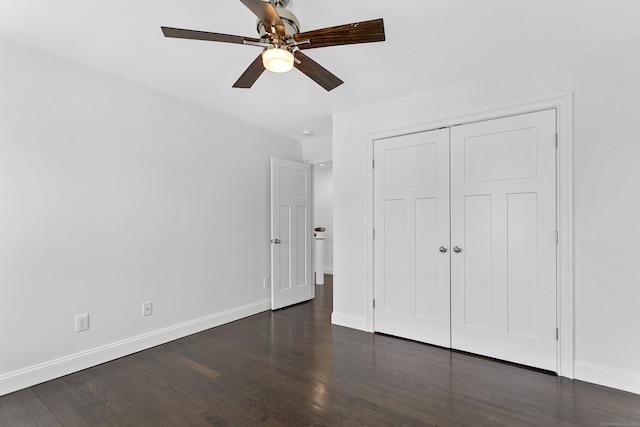 unfurnished bedroom featuring baseboards, dark wood-type flooring, a closet, and ceiling fan