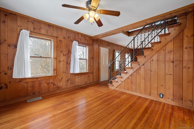 foyer featuring wooden walls, visible vents, a ceiling fan, stairway, and hardwood / wood-style floors