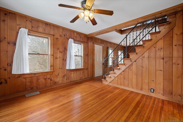 foyer entrance featuring wood walls, stairway, visible vents, and hardwood / wood-style floors