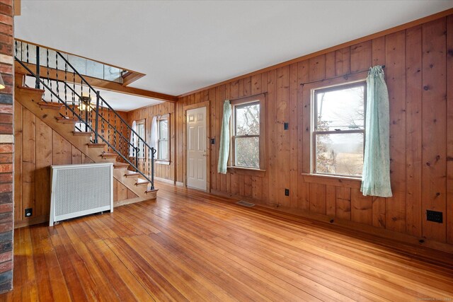 entryway with visible vents, wooden walls, stairway, radiator heating unit, and hardwood / wood-style floors
