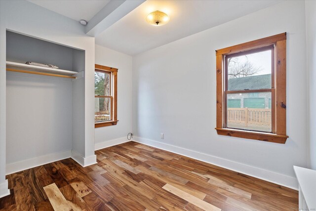unfurnished bedroom with wood finished floors, baseboards, and a closet