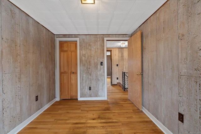 spare room featuring wooden walls, baseboards, and wood finished floors