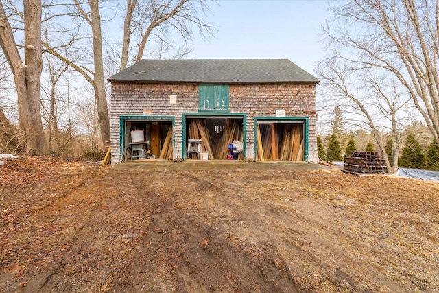 exterior space with a shingled roof, a detached garage, and an outdoor structure