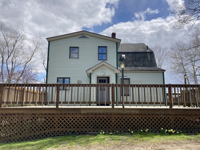 back of house featuring a deck, a shingled roof, and a chimney