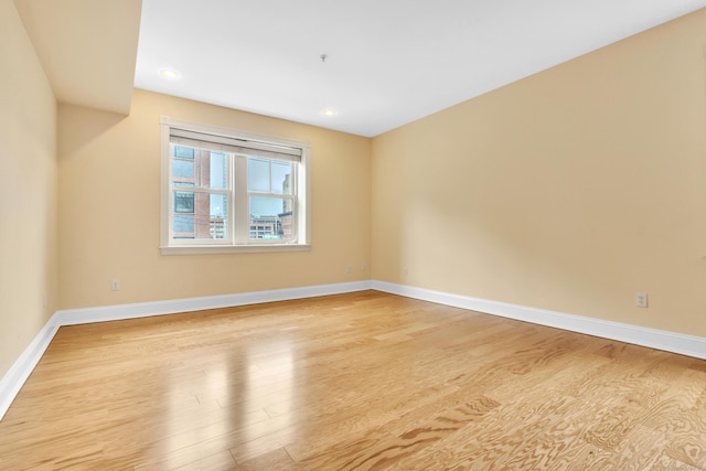 spare room featuring light wood-style floors, recessed lighting, and baseboards