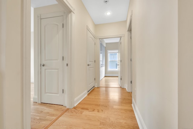 hallway with light wood finished floors and baseboards