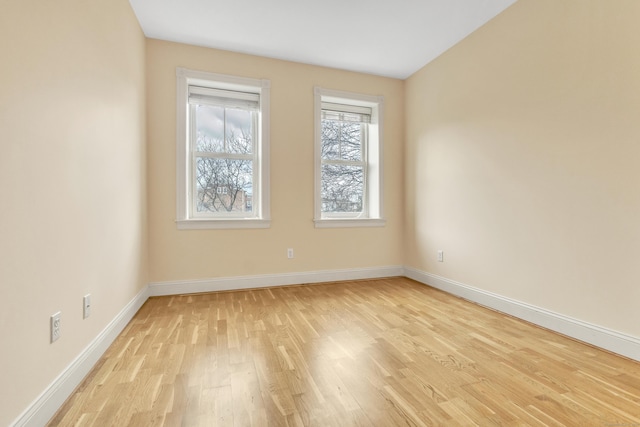 spare room featuring baseboards and light wood finished floors