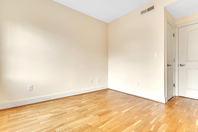 unfurnished room featuring visible vents, light wood-style flooring, and baseboards