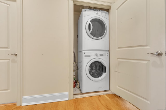 clothes washing area with laundry area, light wood-style floors, and stacked washer and clothes dryer