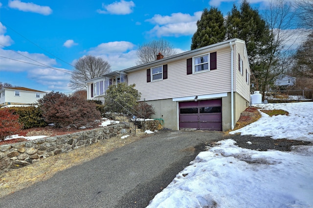 view of front of home featuring an attached garage, driveway, and a chimney