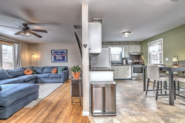 kitchen with plenty of natural light, dark countertops, appliances with stainless steel finishes, open floor plan, and under cabinet range hood