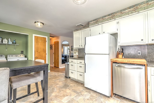 kitchen with dark countertops, visible vents, freestanding refrigerator, white cabinetry, and dishwasher