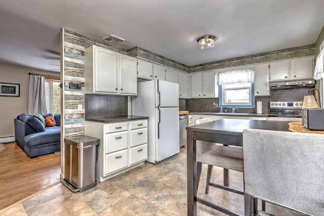 kitchen with stainless steel appliances, dark countertops, visible vents, backsplash, and under cabinet range hood