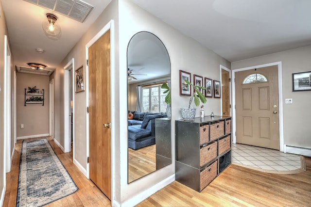 entryway with light wood finished floors, baseboards, visible vents, ceiling fan, and baseboard heating