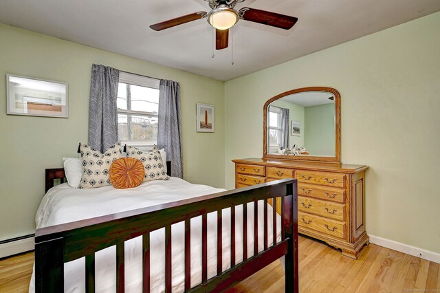 bedroom featuring ceiling fan, baseboard heating, light wood-type flooring, and baseboards