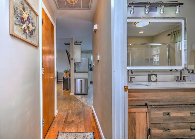 hall featuring wood finished floors, a sink, and visible vents